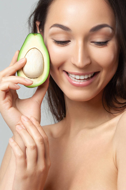 Young beautiful woman holding avocado.  Beauty, youth, skin care - Фото, зображення