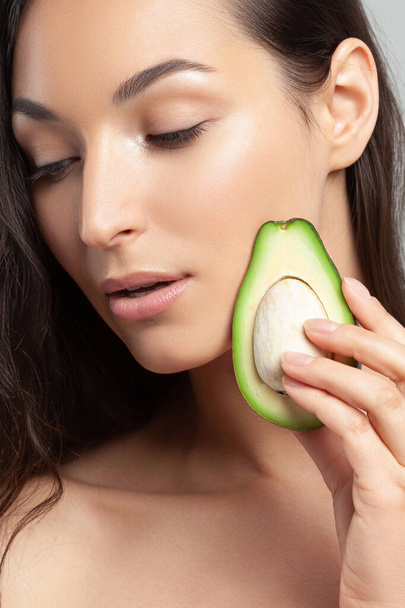 Young beautiful woman holding avocado.  Beauty, youth, skin care - Photo, image