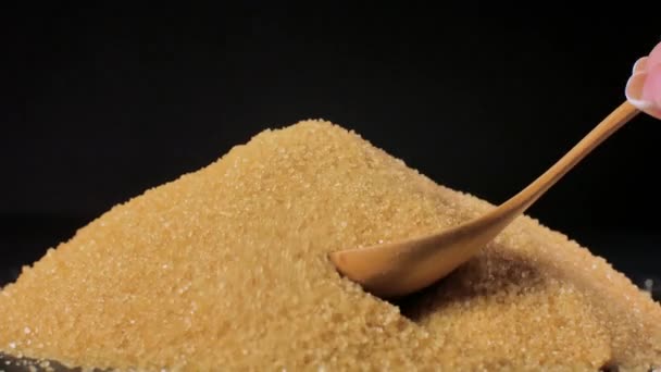 Zucchero di canna non raffinato. Un mucchio di zucchero viene mescolato con un cucchiaio di legno
. - Filmati, video