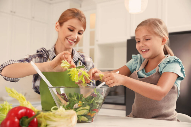 Mother and daughter cooking salad together in kitchen - Foto, Bild