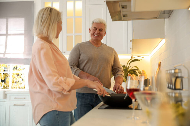 Mature couple cooking food together in kitchen - Foto, imagen