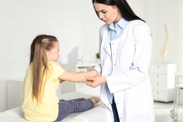 Professional orthopedist examining little patient's arm in clinic - Photo, image