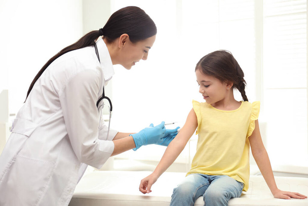 Doutor vacinando criança na clínica moderna
 - Foto, Imagem