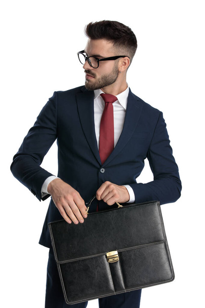 bel homme d'affaires portant des lunettes debout et tenant la mallette tout en regardant de côté cool sur fond de studio blanc
 - Photo, image