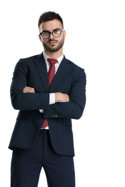 fiatal üzletember visel szemüveget álló karok keresztbe mellkas és feltűnő egy pózt stílus fehér stúdió háttér - Fotó, kép