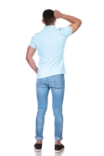 rear view of a man scratching his head and thinking of a situation in a studio with white background - Photo, Image