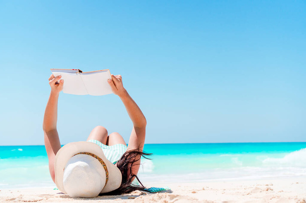 Joven mujer leyendo libro durante tropical blanco playa - Foto, Imagen