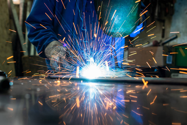 Welder in his workshop welding metal - Foto, imagen