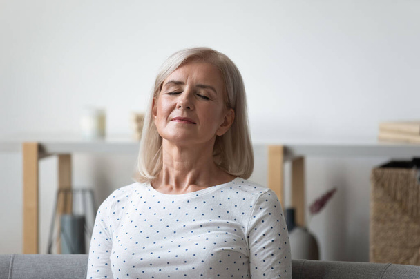 Peaceful middle aged blonde woman relaxing with closed eyes. - Fotoğraf, Görsel
