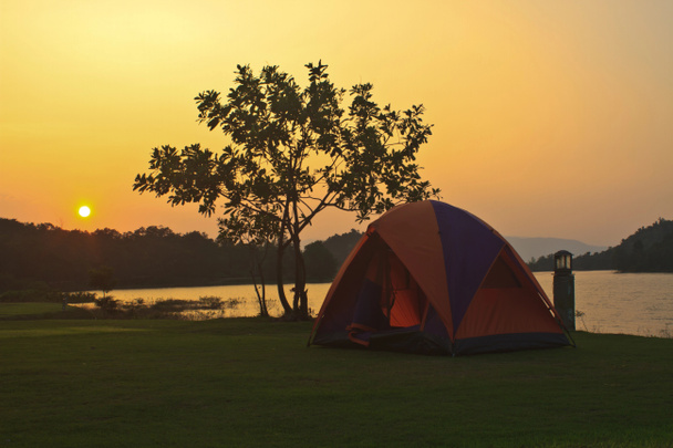 Camping grond en zonsondergang in lake - Foto, afbeelding