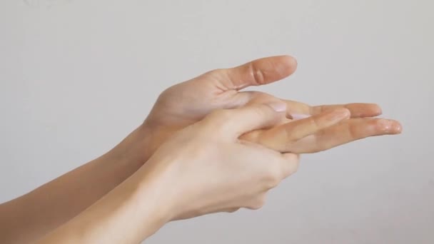 Manos femeninas aplicando crema de manos sobre pared gris
 - Metraje, vídeo