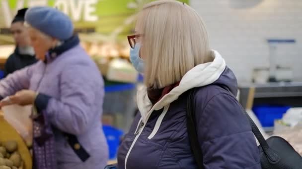 Vieja con máscaras médicas está de compras en el supermercado en busca de la comida
 - Metraje, vídeo