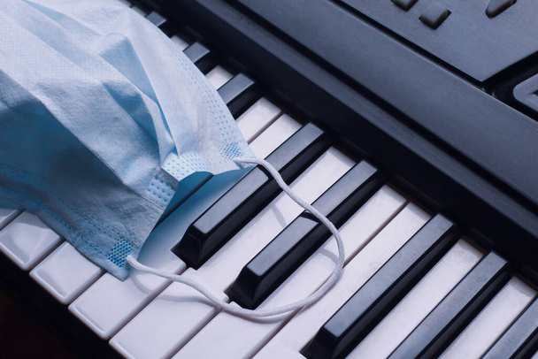 Piyanonun tuşlarında tıbbi maske, arka plan, ton - Fotoğraf, Görsel