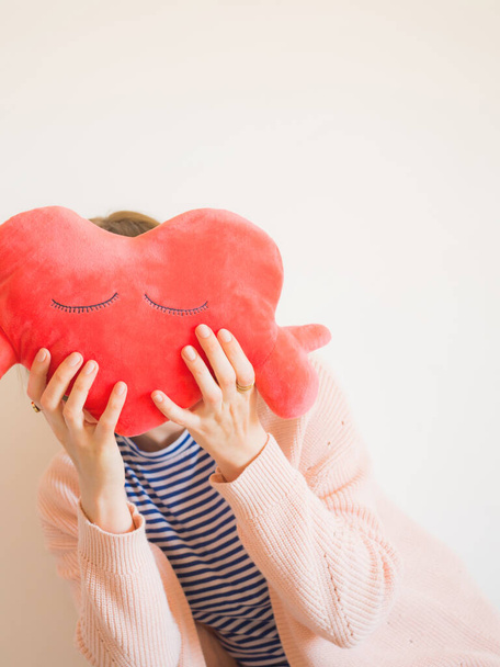 Безликая женщина, покрывающая лицо игрушкой из красного сердца - Фото, изображение