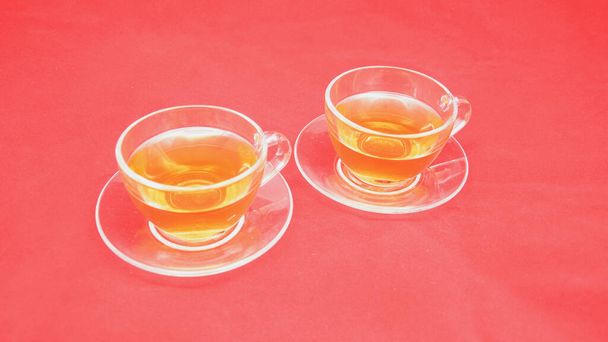 Kaksi kuppia vihreää teetä punaisella taustalla
 - Valokuva, kuva