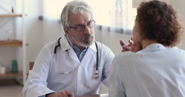 Friendly senior male doctor wear white coat consulting female patient - Felvétel, videó