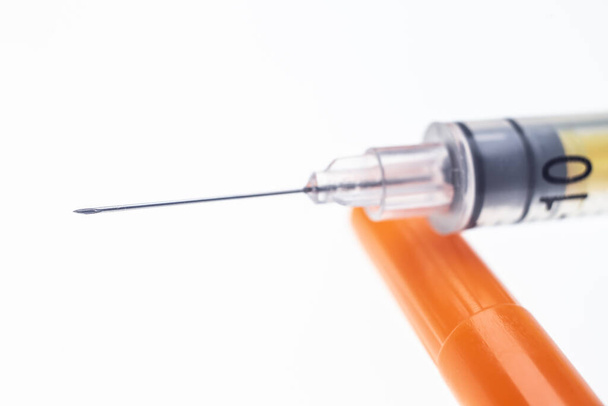Insulinespuit naald met een druppel op een witte achtergrond - Foto, afbeelding