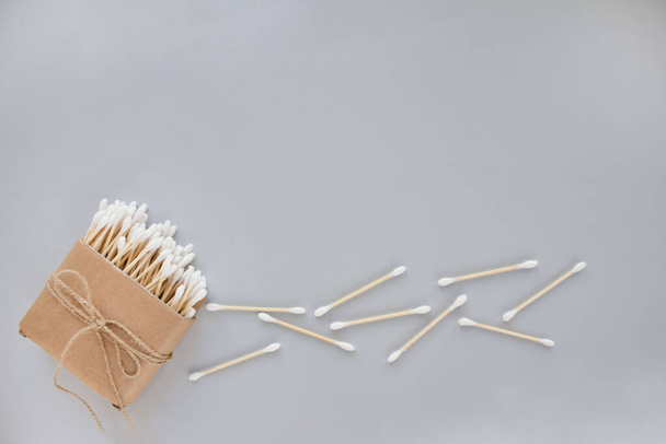 Bambus-Baumwollstäbchen in Pappschachtel, gebunden mit Flachs oder Hanfschnur auf grauem Hintergrund. Kopierraum, Attrappe, umweltfreundliches Konzept - Foto, Bild