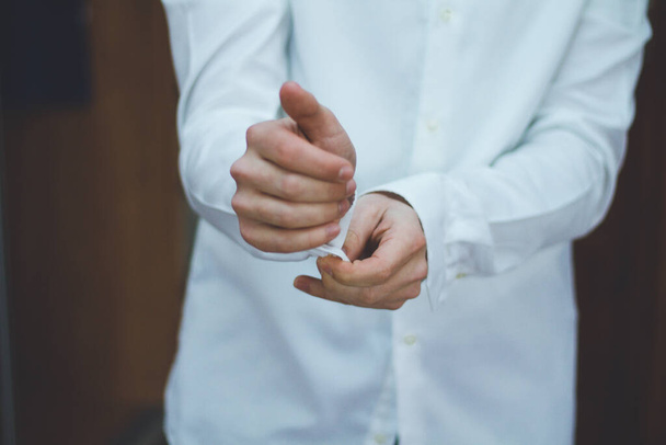 Jovem bem sucedido cara endireita sua manga em uma camisa branca
 - Foto, Imagem