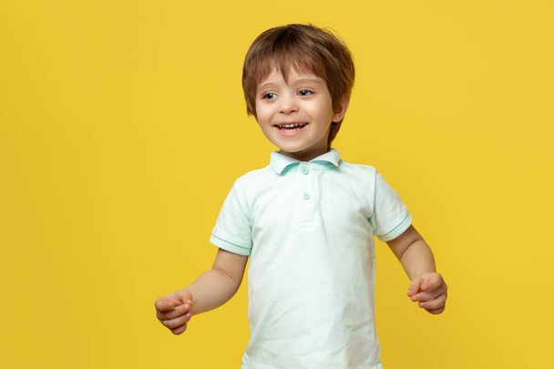 Adorable little kid in casual summer outfit with bright smile posing over yellow background. - Fotó, kép