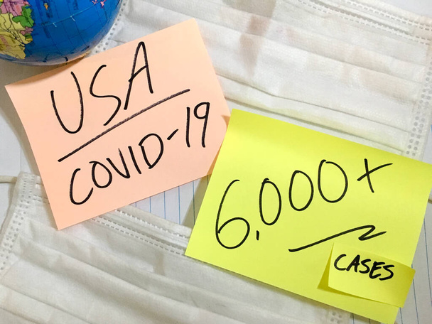 USA Coronavirus COVID-19 infection medical cases and deaths United States. China COVID respiratory disease influenza virus statistics hand written on surgical mask and earth globe background - Φωτογραφία, εικόνα