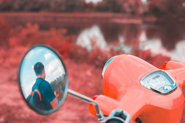Reflectie van een man in de zijspiegel van een motorfiets - Foto, afbeelding