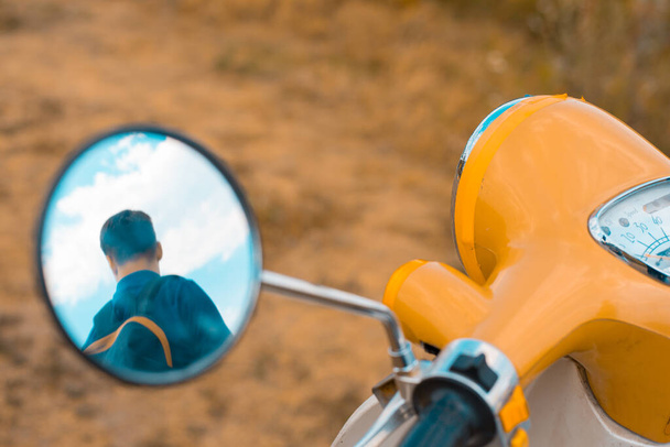 Spiegelbild eines Mannes im Seitenspiegel eines Motorrads - Foto, Bild