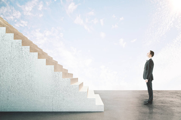 Businessman looking on abstract stairs on blue sky  background. Career development and job concept - Foto, Bild