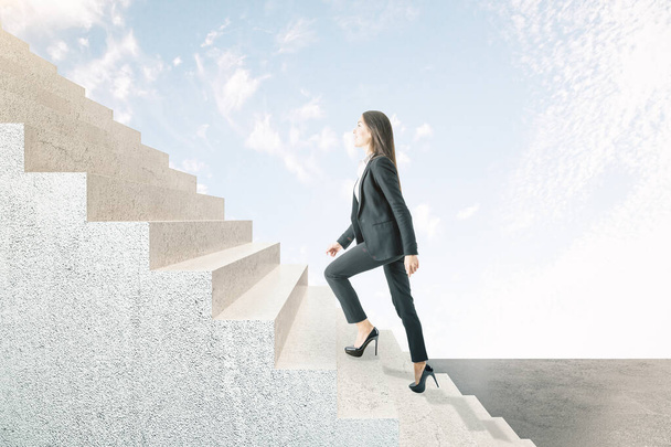 Young businesswoman climbing abstract stairs on sky background. Career development and job concept - 写真・画像