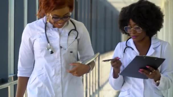 W szpitalu, zajęci afrykańscy lekarze rozmawiają, przechodząc przez budynek. Nowoczesna, w pełni funkcjonalna placówka medyczna - Materiał filmowy, wideo