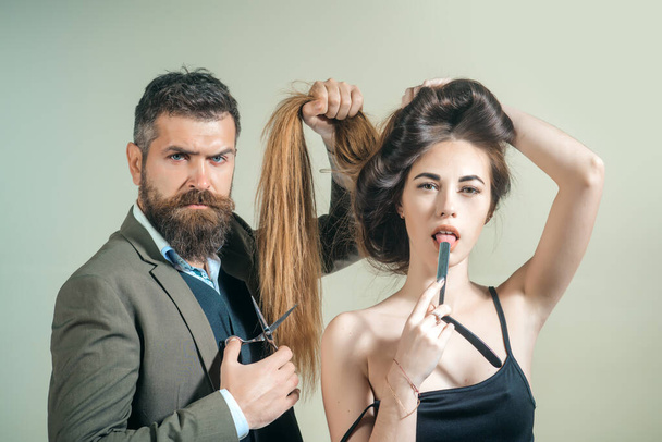 Bearded handsome hair stylist going to cut split ends of sexy woman hair. Adorable woman with long hair visiting her professional hairdresser. Fashion and beauty concept. - Φωτογραφία, εικόνα