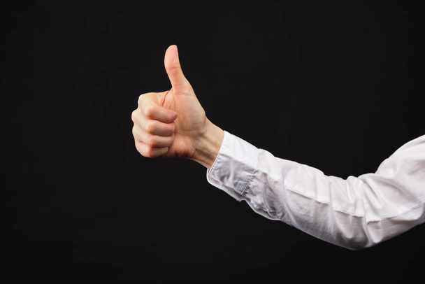 Caucasian businesswoman in a white shirt on a black background. Shows a gesture thumbs up. Close up. Copy space. - Foto, Imagem