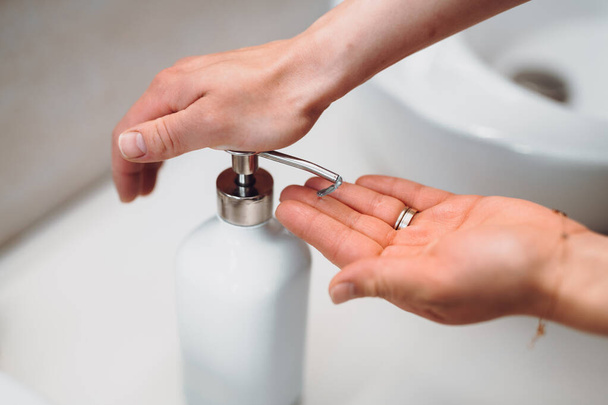 woman using soap dispenser for washing hands during wordwide pandemic, coronavirus - Valokuva, kuva