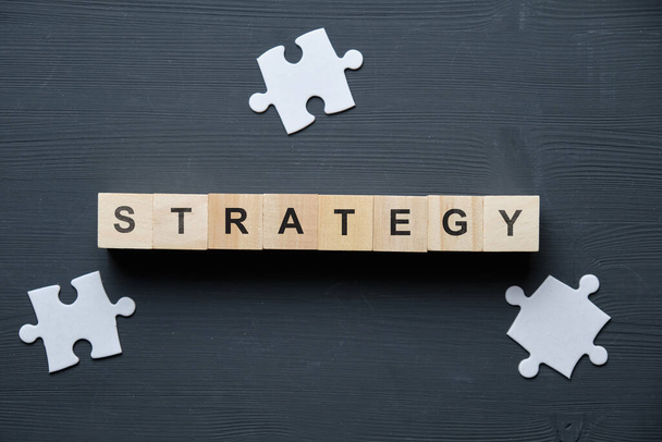 Modern business buzzword - strategy. Top view on a board with a puzzle and wooden blocks. Close up. Top view. - Photo, Image