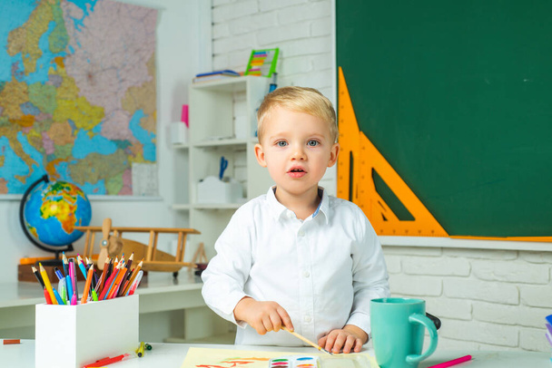 After school teaching. Elementary school and education. Happy cute industrious child is sitting at a desk indoors. - Photo, image