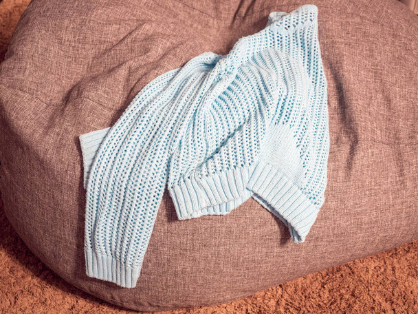 Blauw visnet gebreide trui rust op een grijze stoelenzak - Foto, afbeelding