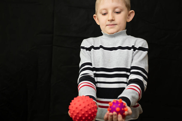 Kleine jongen op zijn hoede kijkt naar virus model in zijn handen - Foto, afbeelding
