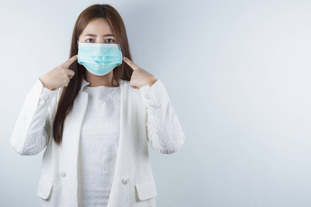 The business woman wearing protection face mask against coronavirus, PM 2.5 and cold, and her finger point on her mask. - Photo, Image