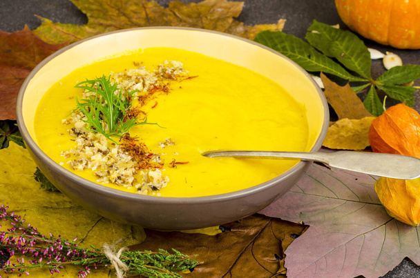 Hot pumpkin soup on background of dried autumn leaves. Studio Photo - Foto, afbeelding