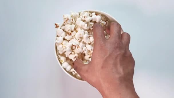  high angle view of mans hand eating popcorn in a bowl and - Filmati, video