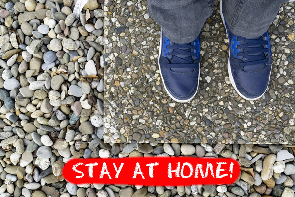 Koncepció Corona válság lábakkal farmer kék cipőben, álló a zsindely, szöveg megjelenítése - Maradj otthon - Fotó, kép
