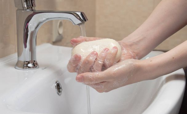 Higiénia. Kezek tisztítása. Szappannal mosok kezet. Női kéz fehér szappannal és habbal. Védekezzen a coronavirus COVID-19 pandémia ellen. - Fotó, kép
