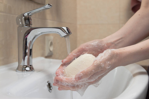 Гігієна. Очищення рук. Миття рук з милом. Жіноча рука з білим милом і піною. Захистіть себе від пандемії коронавірусу COVID-19
. - Фото, зображення