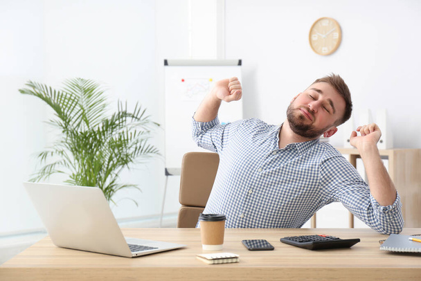 Lazy young office employee stretching at workplace - Foto, immagini