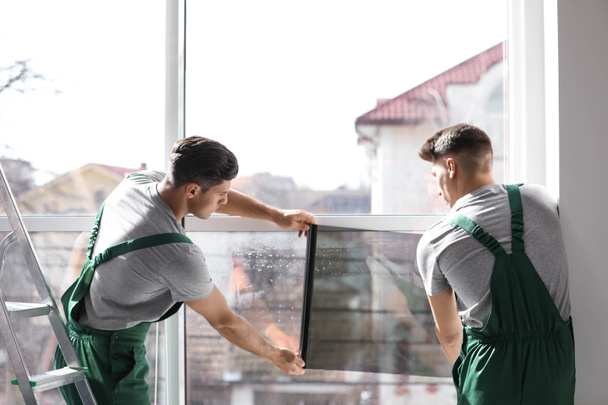 Professional workers tinting window with foil indoors - Photo, image