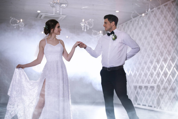 Ευτυχισμένο ζευγάρι νιόπαντρων που χορεύουν μαζί στην εορταστική αίθουσα - Φωτογραφία, εικόνα