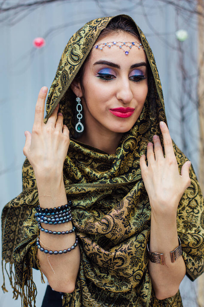 Close up portrait of a beautiful eastern woman with bright makeup and jewelry wearing headscarf. - Foto, Bild