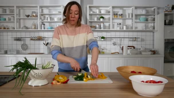 girl dancing and slicing vegetables in the kitchen - Filmati, video