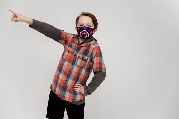 Photo of a masked boy in a plaid shirt on a white background shows his hands to the sides - Foto, immagini