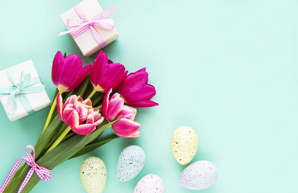 Flores de tulipa primavera, ovos de Páscoa e caixa de presente em fundo verde pastel. Saudação para a Páscoa. Vista superior, flat lay
. - Foto, Imagem